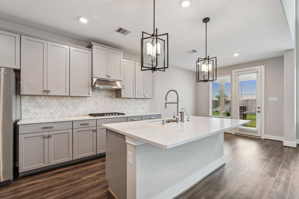 Beautiful light and bright kitchen with spacious center island and room for seating, modern pendant lighting, 5 burner gas cooktop, butler's pantry, and Whirlpool appliances.