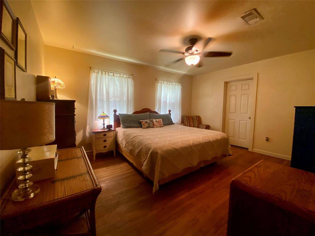Spacious primary bedroom with hardwood floors, a ceiling fan and ensuite bathroom.