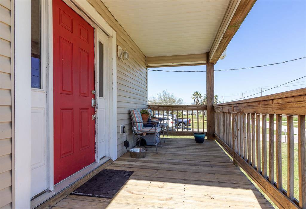 Welcoming front porch with a bright red door and wood decking, providing a cozy space to relax and enjoy the sunrise.