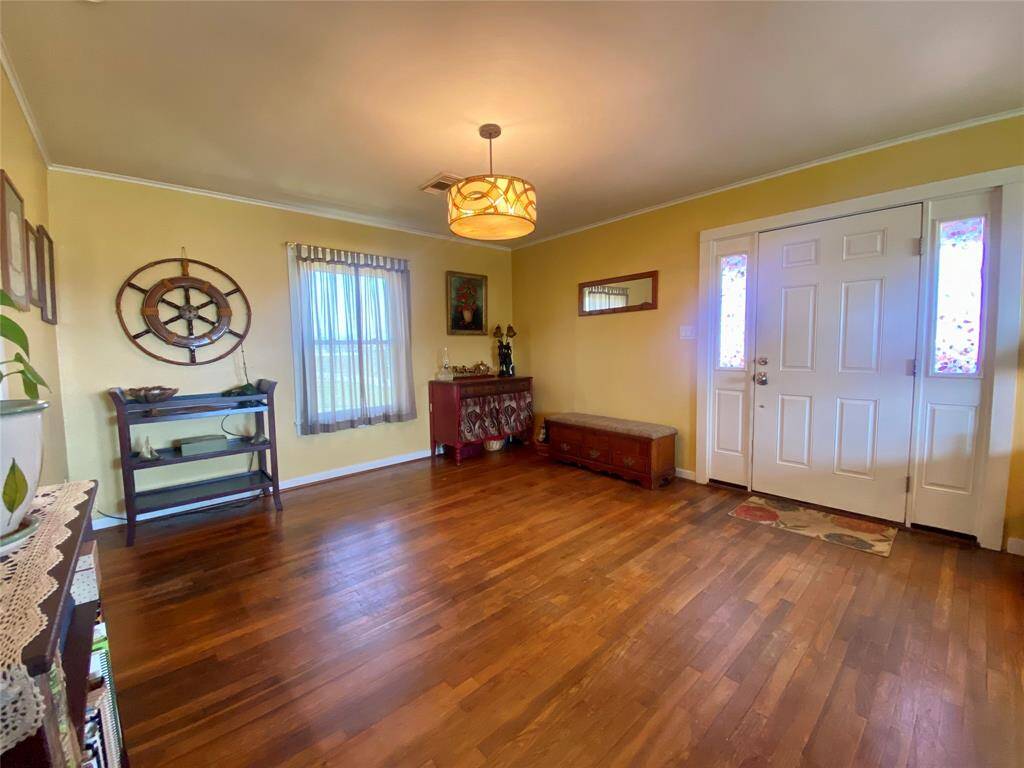 This welcoming entry to the dining area features warm hardwood floors, soft yellow walls, and a charming ceiling light fixture.