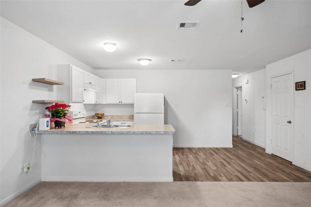 Functional U-shaped kitchen with breakfast bar seating, modern open shelving, and durable countertops—ready for your culinary creations.