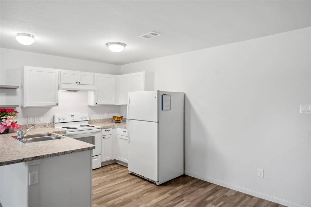Fresh, white kitchen equipped with matching appliances, laminate countertops, and plenty of cabinet storage—functional and modern in design.
