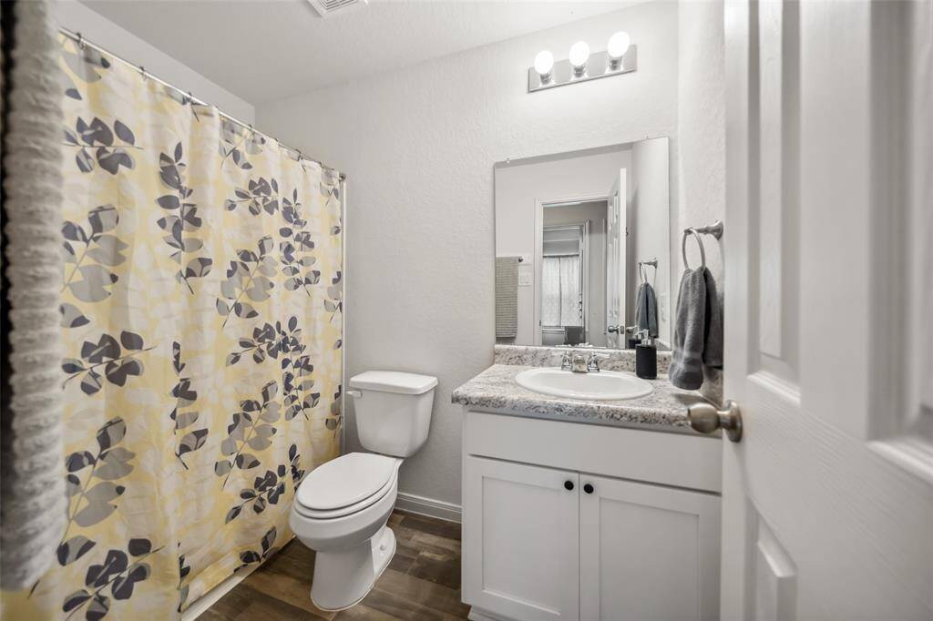 Well-maintained full bathroom with a laminate countertop vanity, modern lighting, and a shower/tub combo.