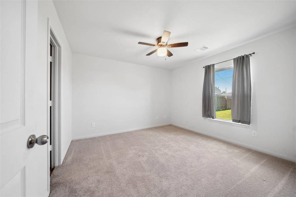 Spacious and bright secondary bedroom featuring ceiling fan, and a large window with views to the backyard.