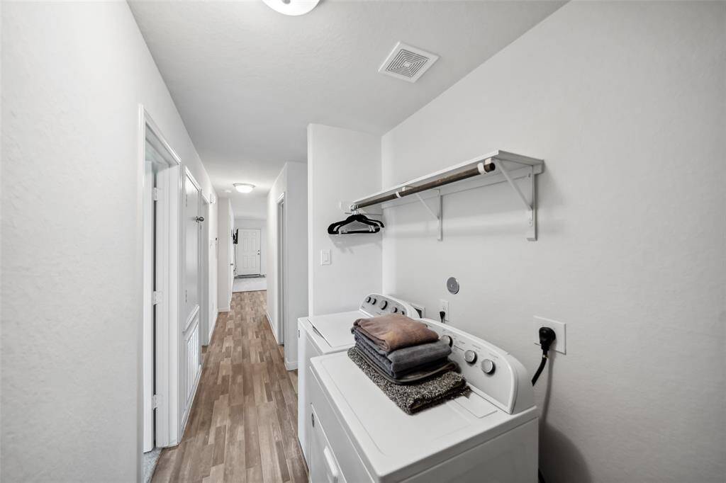 Dedicated laundry space for full-size washer and dryer, overhead shelf, and convenient access to the main hallway.