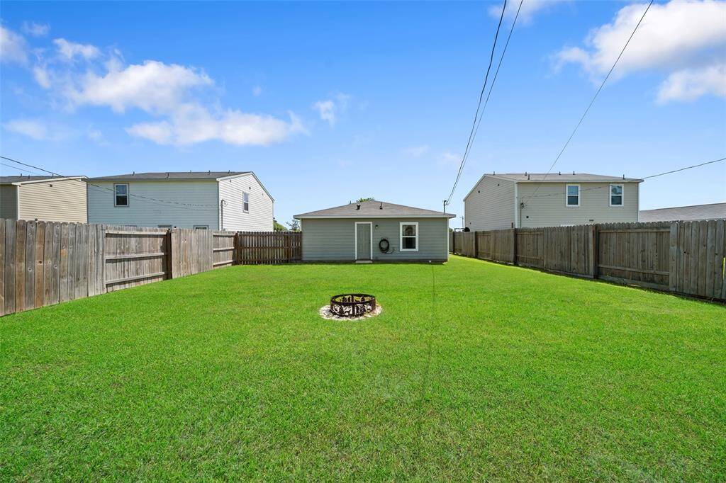 View from the back of the yard highlighting the privacy fence, rear entry, and well-maintained exterior of the home.