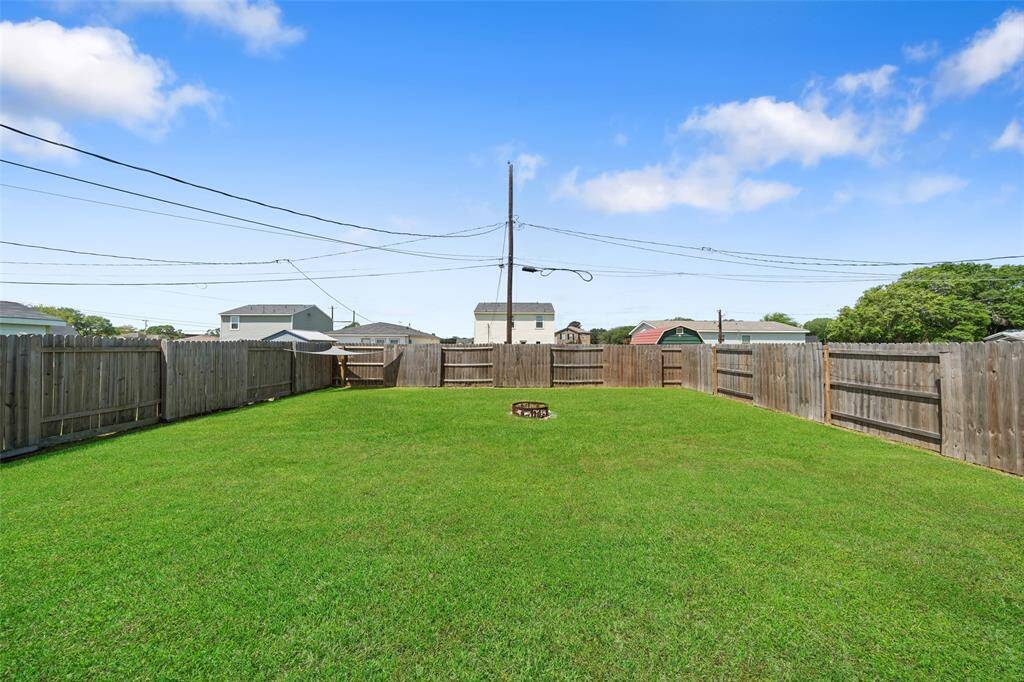 Expansive, fully fenced backyard with lush green grass and a fire pit—ideal for entertaining or outdoor relaxation.