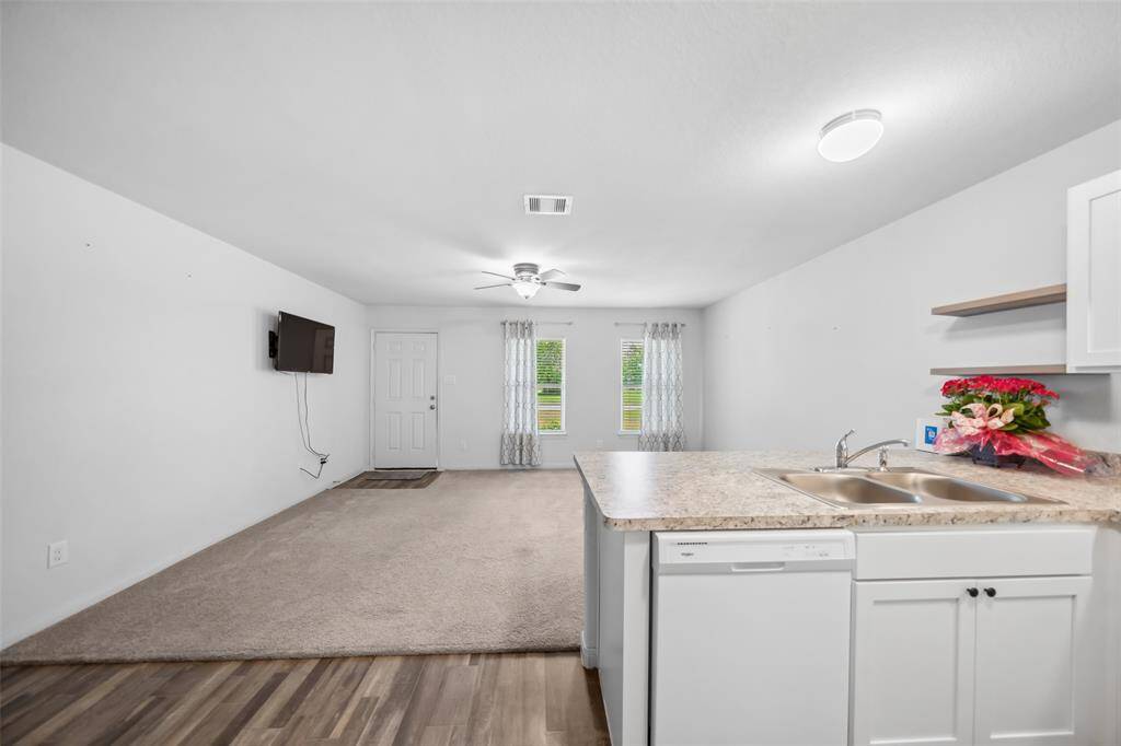 Open-concept floor plan with seamless flow from kitchen to living room. Enjoy carpeted comfort underfoot and abundant natural light from the front-facing windows.