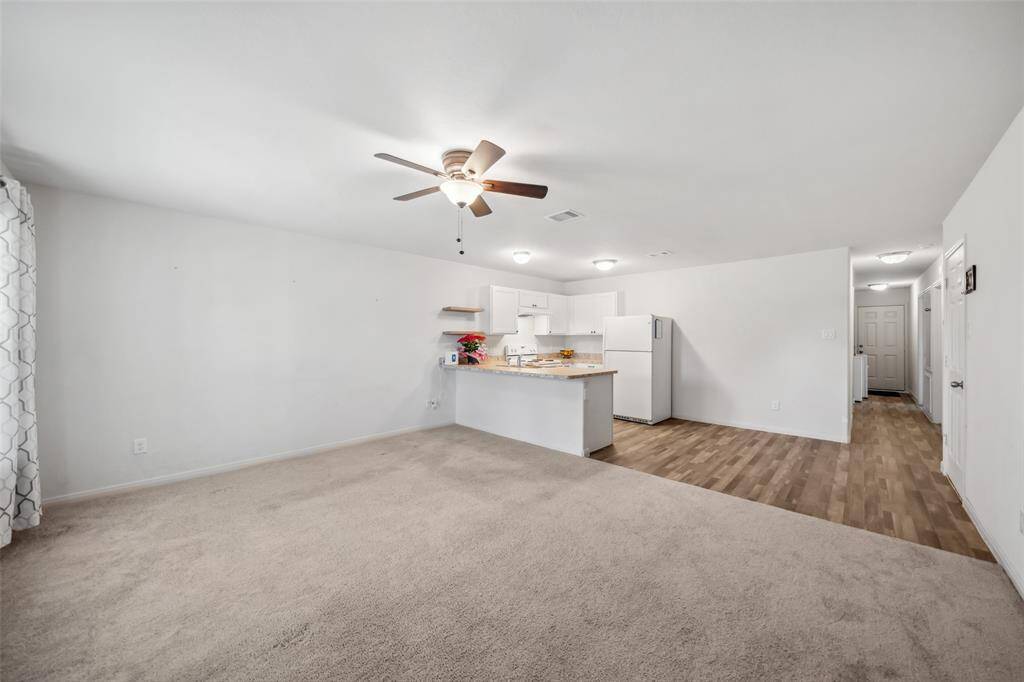 Spacious and flowing layout, with clean white finishes, ceiling fan, and warm lighting throughout the shared living space.