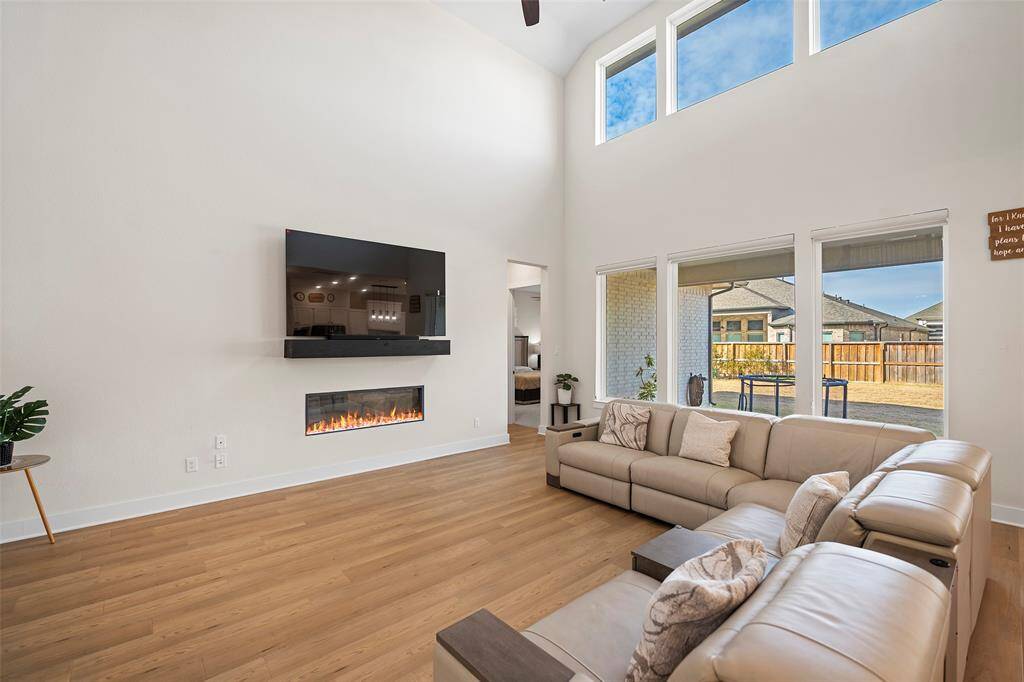Natural light floods the living room through oversized windows and clerestory panels, drawing attention to the clean lines, soaring ceilings, and a sleek linear fireplace that adds warmth and a modern focal point.
