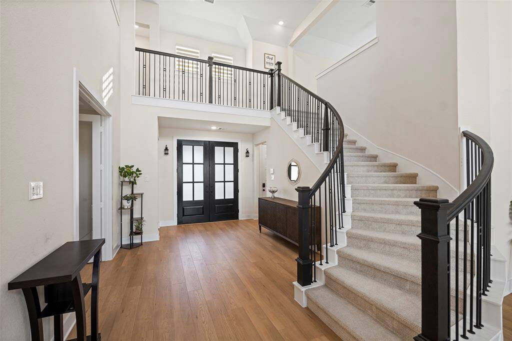 The curved staircase makes a striking first impression, drawing your eye upward toward the second-story landing. Iron spindles and soft carpet lead the way to additional living space above, seamlessly blending form and function in the heart of the home.