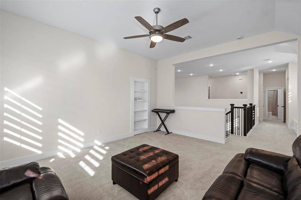 Upstairs flex space features a spacious and versatile layout, ideal for a game room, media area, or second living room. Includes a hidden secret room with an entrance concealed behind the bookshelf. Natural light filters in from multiple directions, and the open railing provides a visual connection to the entry below while keeping the space bright and airy.