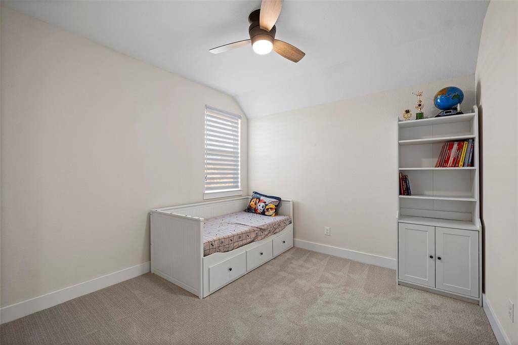 This upstairs secondary bedroom features plush carpet, a modern ceiling fan, and soft natural light—ideal for a guest room, nursery, or playroom setup.