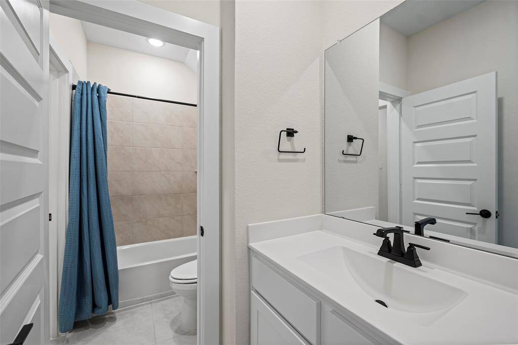 Full bathroom upstairs includes a spacious vanity, sleek black fixtures, and a tub/shower combination with neutral tile surround. Designed as a Jack-and-Jill layout, it connects two bedrooms. Ideal for added privacy and convenience.
