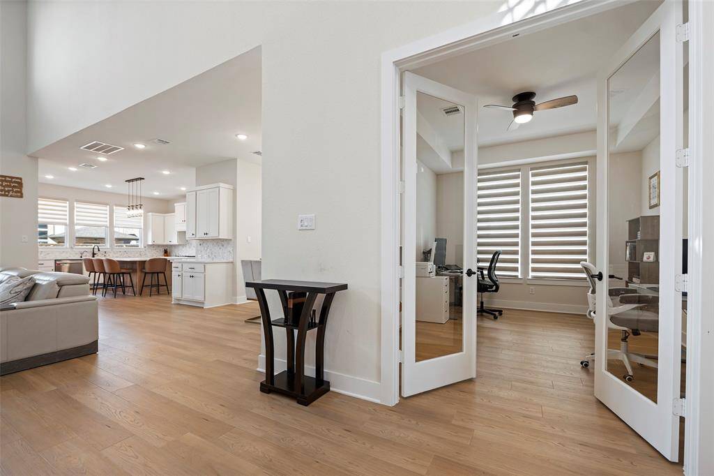 Just off the entry, a glass-enclosed study offers privacy without sacrificing natural light. Clean lines, neutral tones, and oversized windows set the tone for the open-concept living beyond—where the kitchen, dining, and living spaces come seamlessly together for effortless daily living and entertaining.