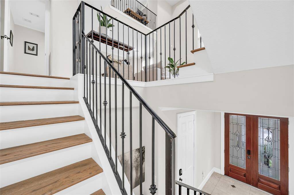 The handsome wrought iron staircase leads you from the welcoming entry to the living room, dining room, and kitchen beyond.