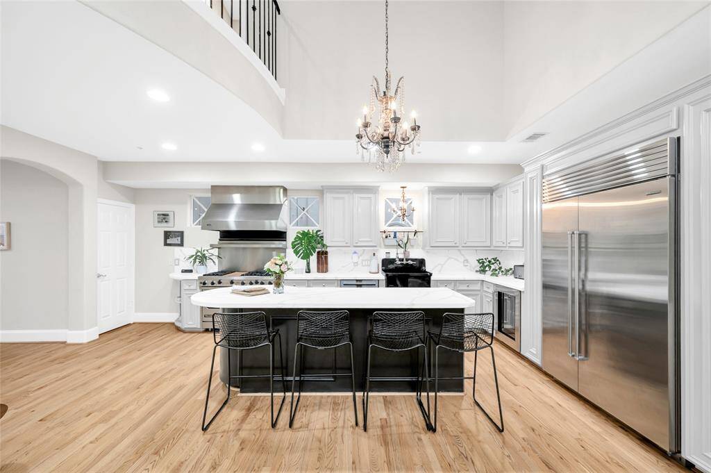 This angle of the kitchen showcases the beautiful quartzite countertops and island with pull-up seating. The classic chandeliers, which convey with the home, punctuate the high-end finishes.