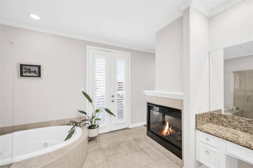 Primary suite bathroom offers a jetted tub, standing shower, double-sink vanity, and even the fireplace is shown.