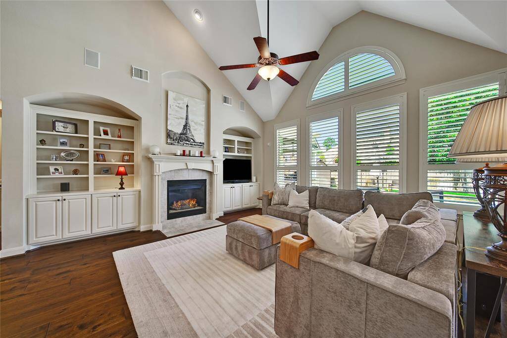 Spacious family room with a view of the outdoor oasis. Custom built-ins, a gas fireplace, wood flooring, and 4" plantation shutters are some of the extras you'll find in this beautiful home.