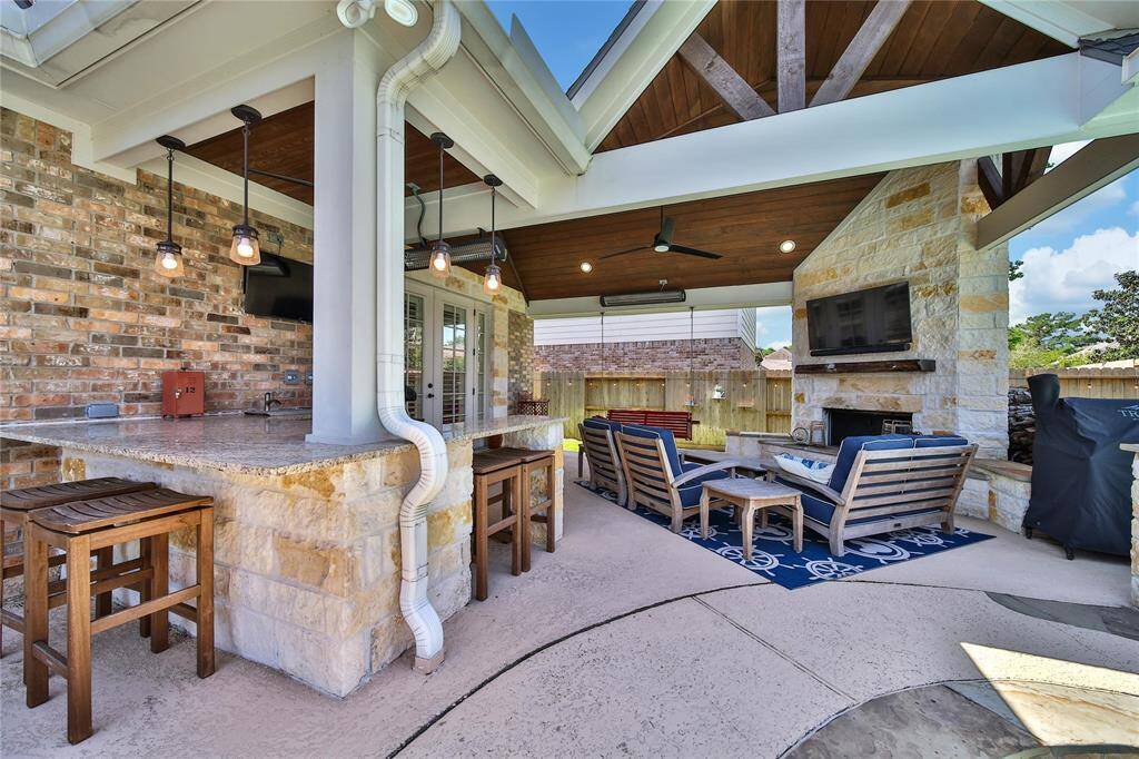 Attention to detail when designing this outdoor space include the custom ceiling, stone fireplace, mounted heaters, and plenty of seating and serving space.