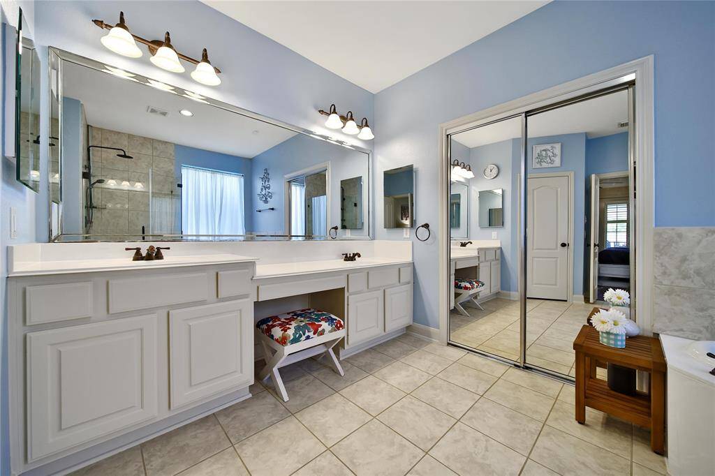 Spa-like bath with double sinks, vanity area, medicine cabinets, and large mirrored doors.