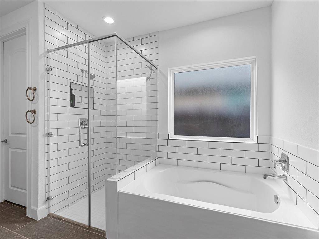 Modern bathroom with a walk-in shower, subway tiles, and a separate tub, featuring a frosted window for natural light and privacy.