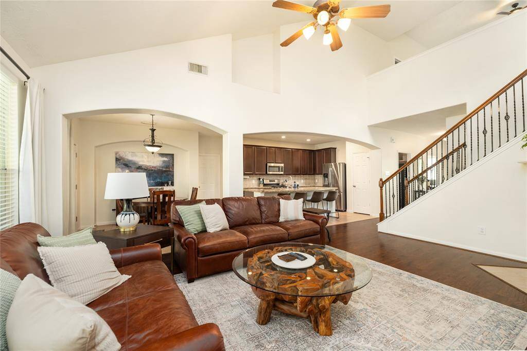 Designed with both comfort and style in mind, this spacious living area showcases soaring ceilings, rich hardwood floors, and an abundance of natural light. An open-concept layout flows seamlessly into the kitchen, while a gracefully detailed staircase adds a touch of architectural charm, leading to the upper level of this beautifully maintained home.