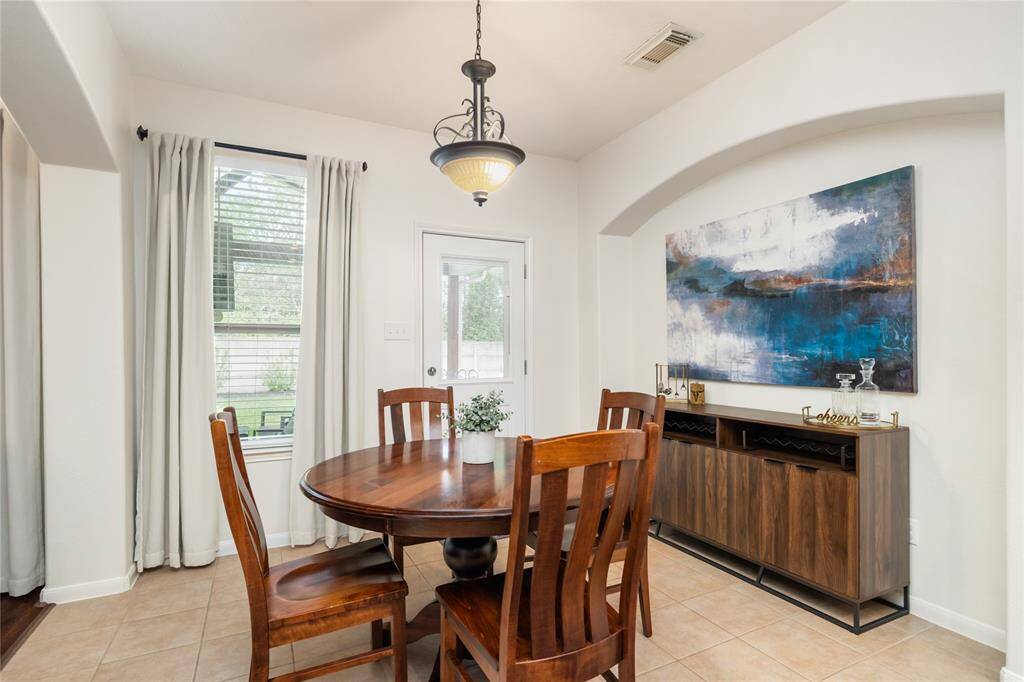 Nestled just off the kitchen, this light-filled dining area offers a welcoming space for everyday meals and casual gatherings. Natural light pours in through the large window and glass door, enhancing the open-concept feel and highlighting the clean, neutral palette and modern overhead lighting.