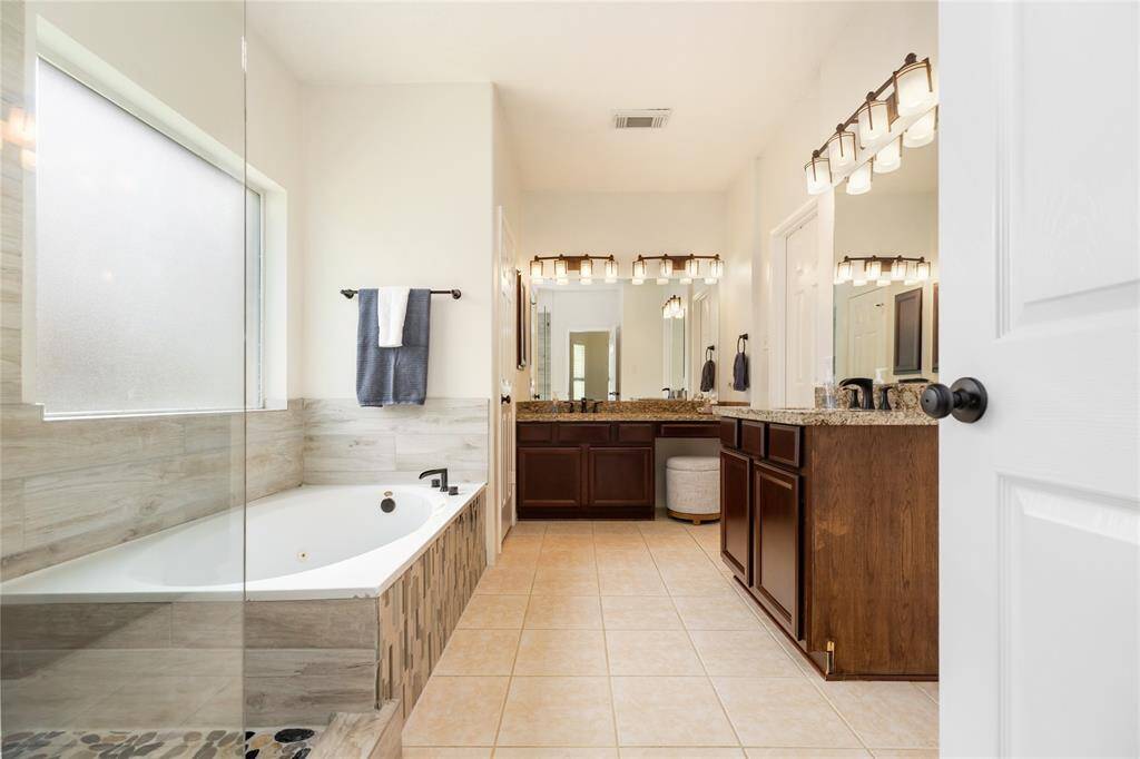 This meticulously maintained en-suite bathroom combines timeless elegance with a warm, inviting atmosphere. The spacious layout features a luxurious soaking tub, a double vanity with granite countertops, and modern lighting, all bathed in natural light. The separate shower area adds to the home's beautiful functionality, making this a truly serene retreat.