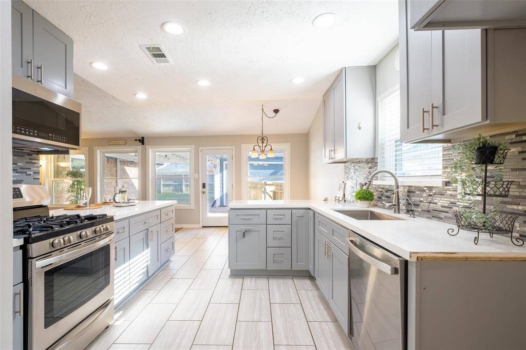 Bright, modern kitchen with stainless steel appliances. The open layout leads to a sunlit patio area, perfect for entertaining.