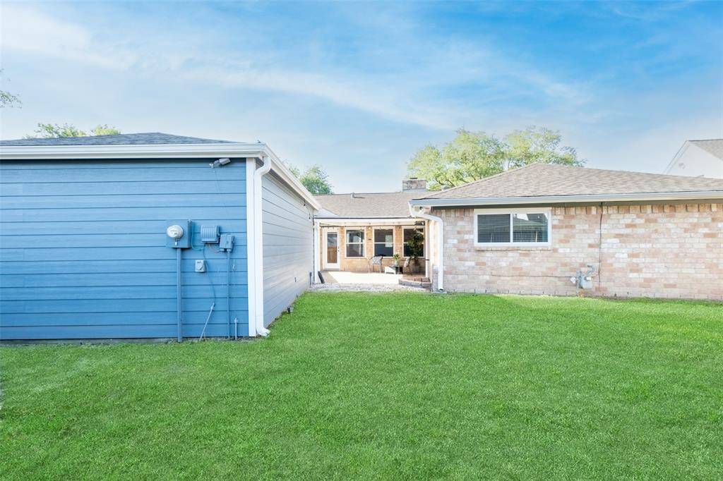 This photo shows a spacious backyard . It includes a small patio area leading to the house, ideal for outdoor relaxation.