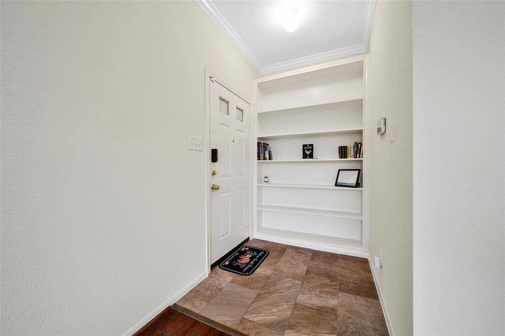 The foyer features durable tile flooring and a floor to ceiling built-in for storage and display.