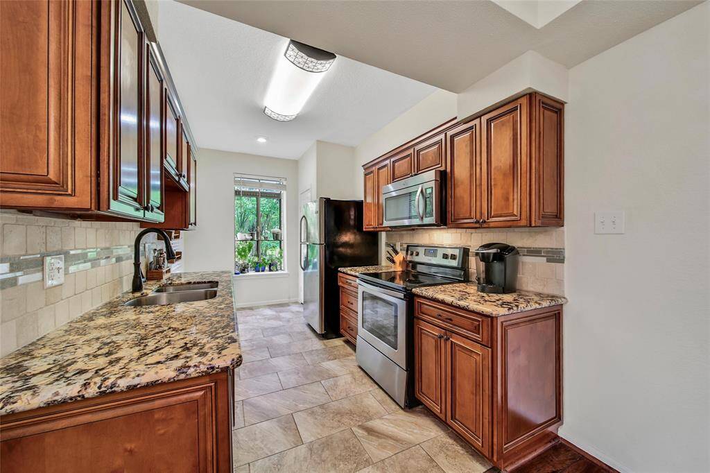 The kitchen was thoughtfully remodeled with premium finishes including gleaming raised panel wood cabinetry, granite counters, a mosaic backsplash and stainless steel appliances. The tile floor is a durable and worry-free addition to this functional and beautiful kitchen.