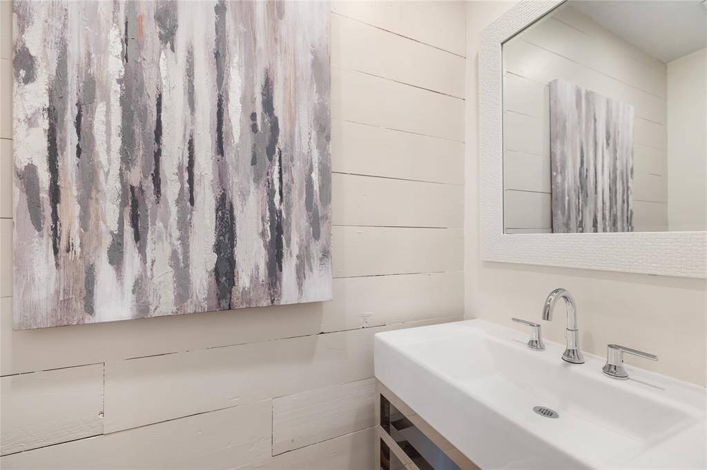 Charming downstairs powder room features quaint shiplap walls.