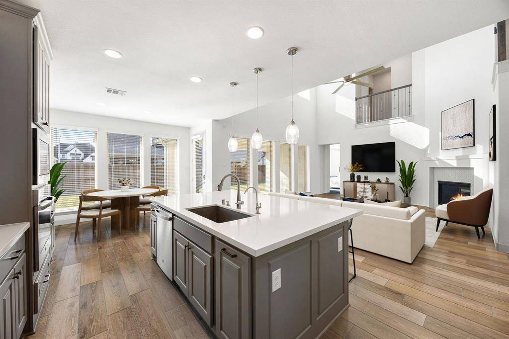 This stunning kitchen displays such a beautiful contrast with the dark stained cabinets, custom neutral paint, granite countertops, light modern backsplash, and SS appliances, oversized kitchen island with extra storage, breakfast bar, recessed lighting, high ceilings and walk in pantry.