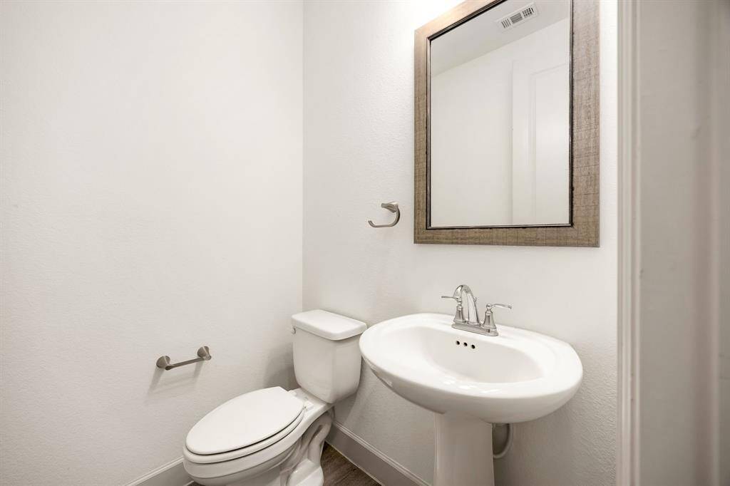 Sleek half bath featuring a contemporary pedestal sink and a rustic framed mirror for added style.
