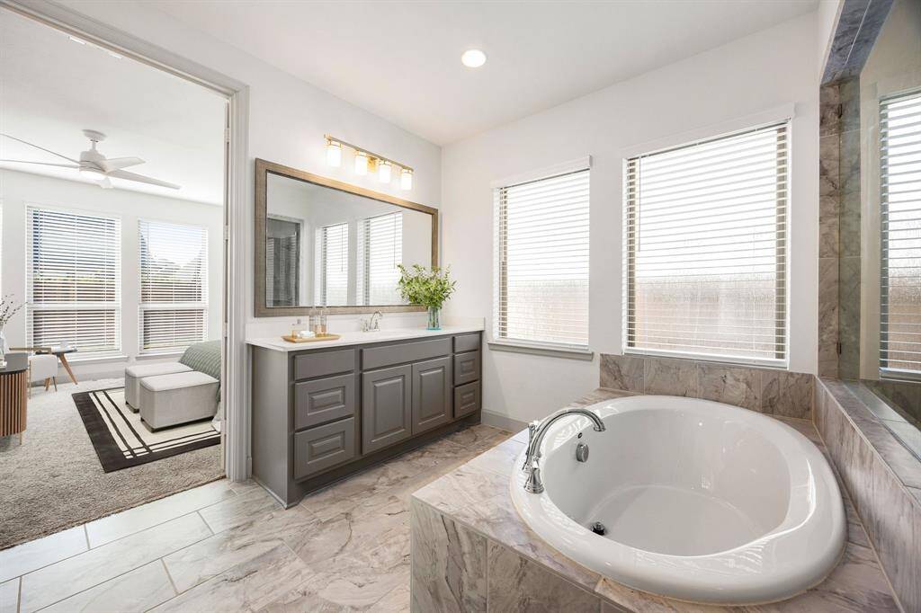 This primary bathroom is definitely move-in ready! Showcasing a luxurious soaking tub with modern tile surround and abundant natural light.