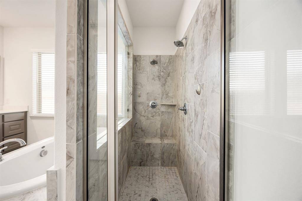 Large walk-in shower featuring dual shower heads, custom tile work, and a built-in bench for added comfort.