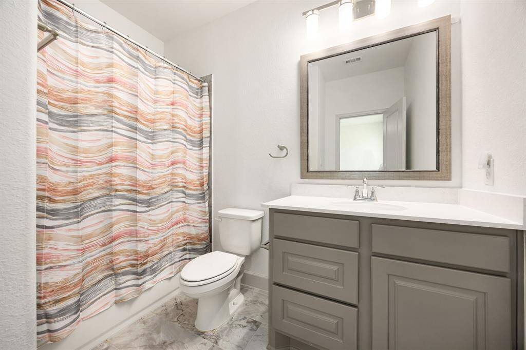 Well-appointed secondary bathroom complete with modern fixtures, ample storage, and an elegant framed mirror.