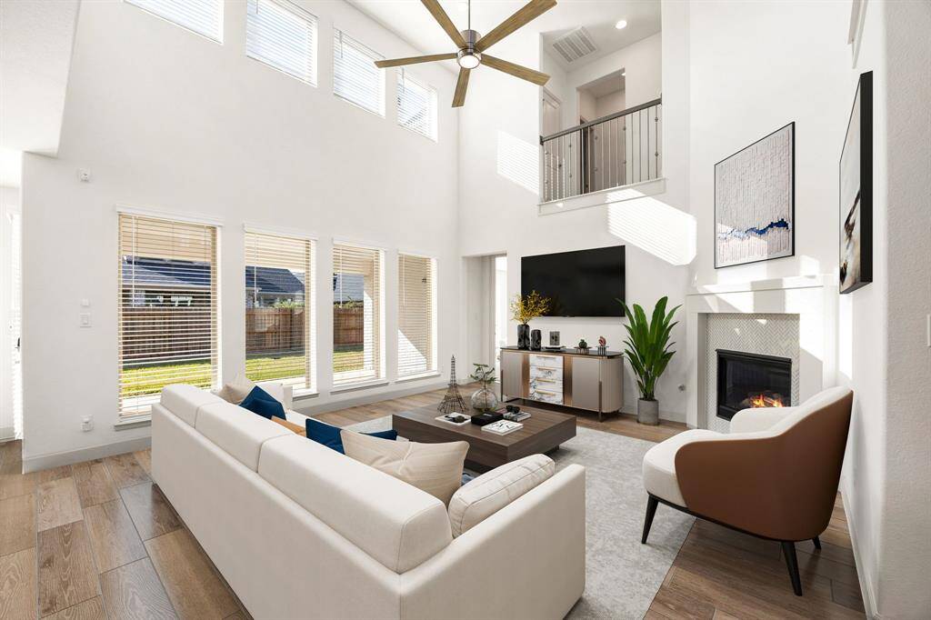 This living room is more like a GREAT room featuring a stunning fireplace with mantel detailing, custom paint, soaring high ceiling, recessed lighting, dark stained ceiling fan, and an amazing wall of windows providing a lovely view of your backyard to keep an eye out on the kids or pets playing. *Virtually Staged