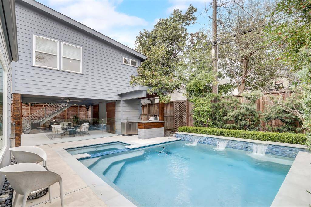 This sparkling pool + hot tub has built-in fountain features as well as access to the outdoor kitchen.
