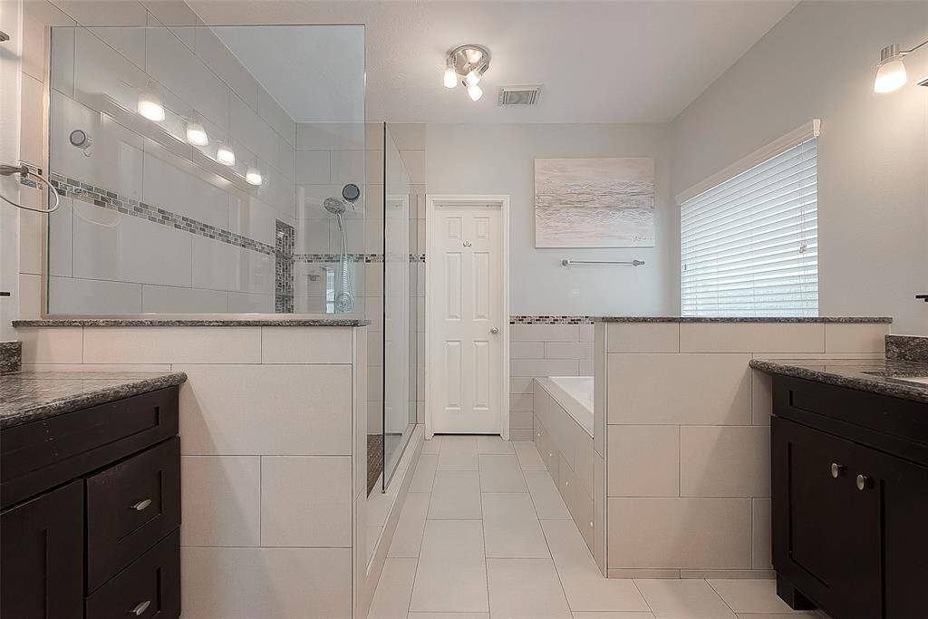 Primary bath boasts his and hers sinks and a separate jetted tub and a large shower.