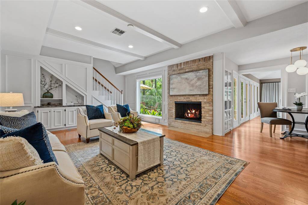 A great view of this Family Room with Beamed Ceiling, Fireplace... Wood Floors... Note how open this all is... and with built-in cabinetry! Rear Entry Staircase... 3 living areas downstairs!!!
