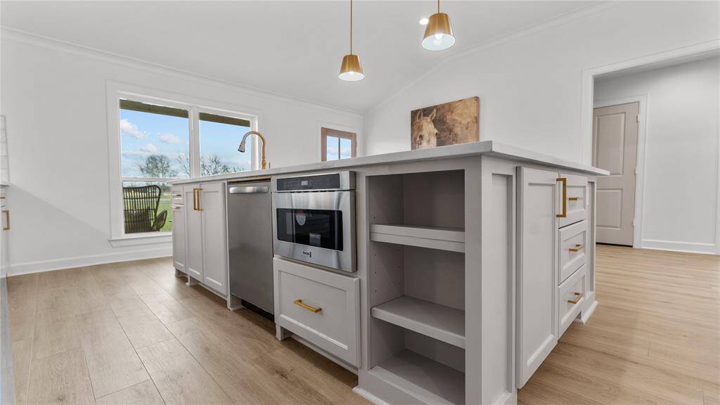In addition to the electric range with an custom venthood, the kitchen boasts otherstainless steel appliances such as a pull out microwave nestled discreetly within the island, and a dishwasher.