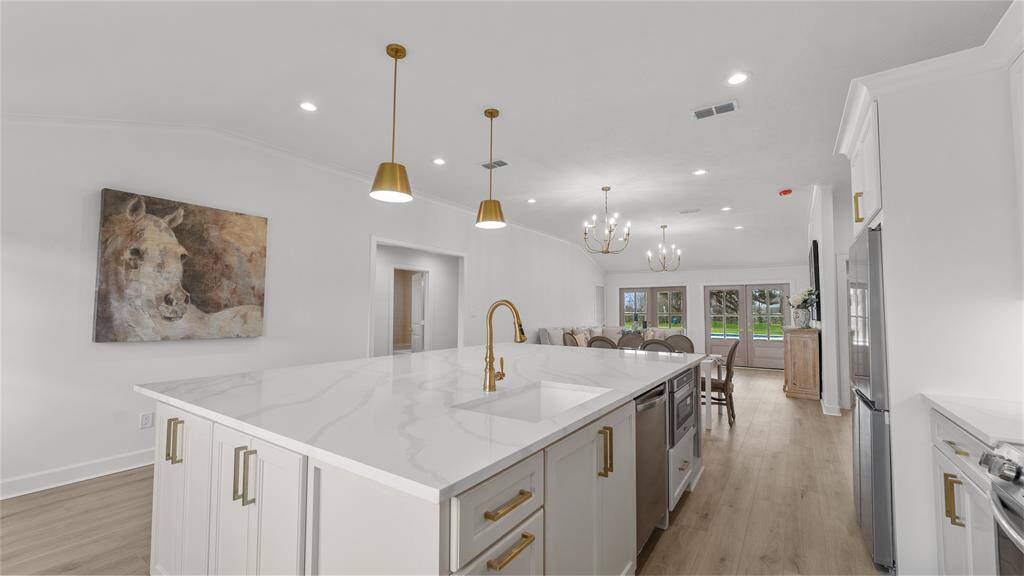 The gleaming gold finish on the faucet lends a sense of warmth and opulence, creating a striking visual contrast against the crisp white sink and surrounding surfaces. Take note of the amount of storage located within the island!