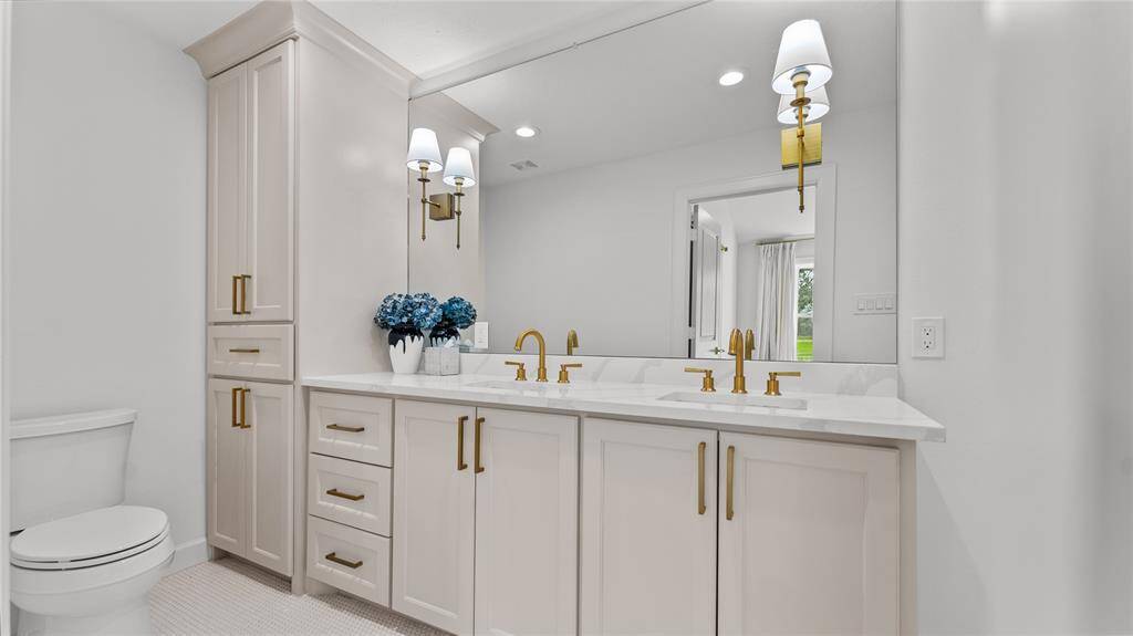 What a stunning ensuite bathroom!The spacious vanity offers dual sinks, beautifully crafted cabinetry and complementing quartzcounters. Check out the elegant lighting fixtures that are built into the frameless mirror.
