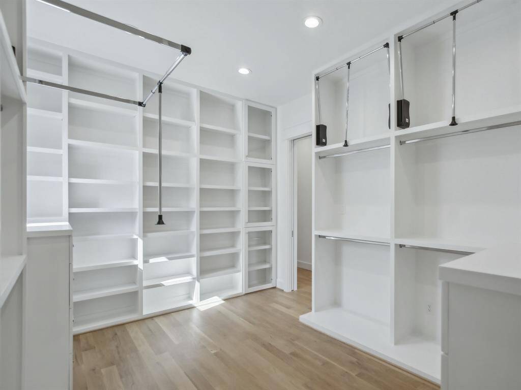 Sunlit primary closet featuring custom built-ins for elegant organization.