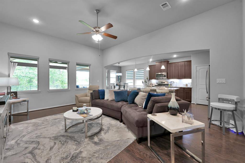 This photo showcases a spacious, open-concept living area with a modern kitchen. The room features large windows for natural light, and sleek hardwood floors.
