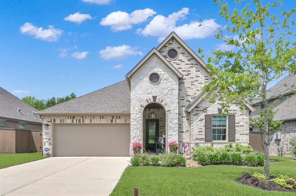Charming single-story home with a stone and brick exterior, manicured lawn, and inviting entryway. Features a spacious garage and well-maintained landscaping under a clear blue sky.