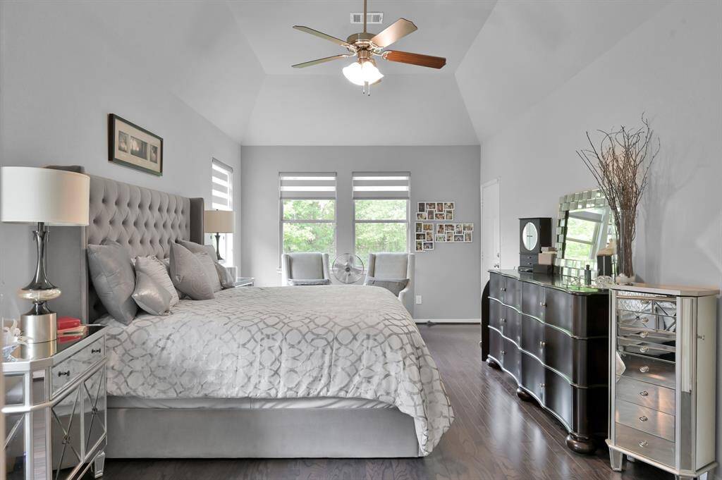 This elegant primary bedroom features a high ceiling and large windows for plenty of natural light, creating a serene and inviting atmosphere.